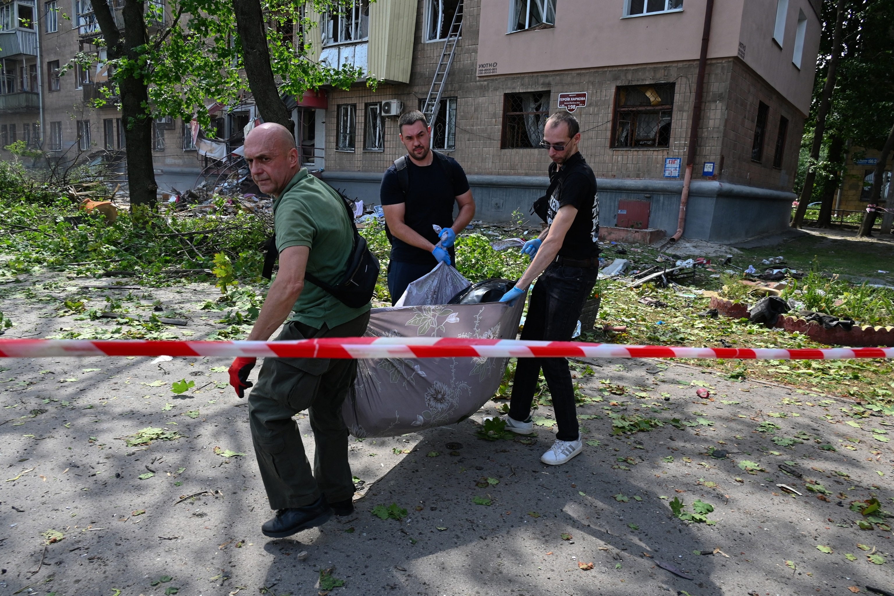 Workers carry the body of a resident outside a damaged residential building following a Russian missile strike in Kharkiv, Ukraine, on July 8, 2026.Sergey Bobok/AFP via Getty Images