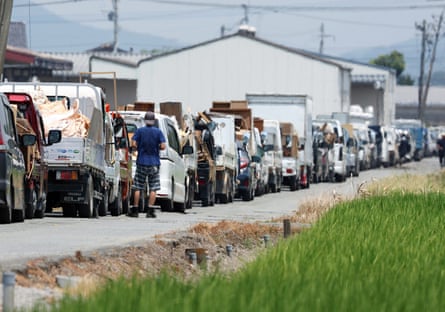 Vehicles wait in line to transport disaster debris to a temporary storage site in Hikawa, amid sweltering temperatures.Photograph: Jiji Press/EPA