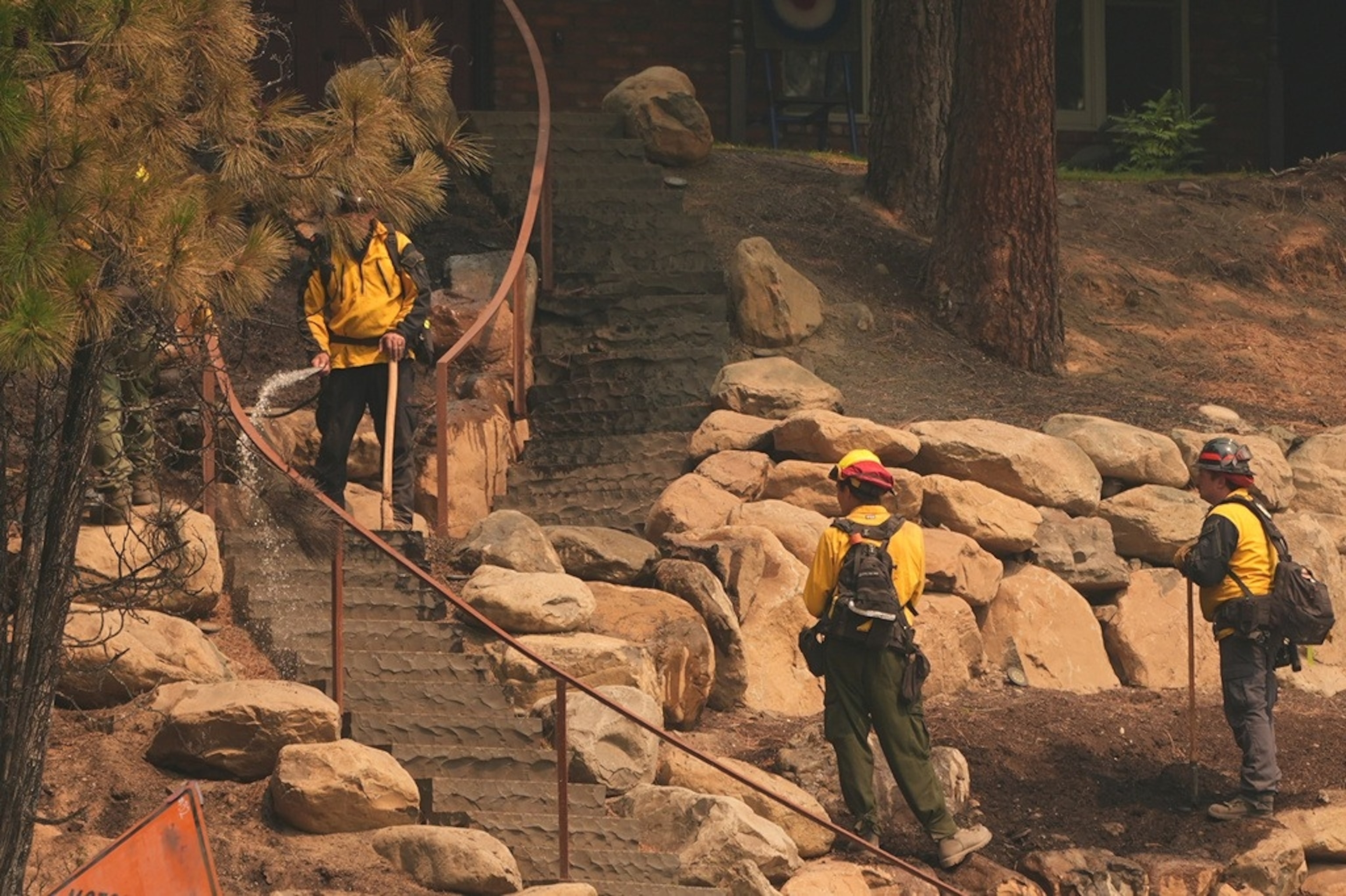 Wildland firefighters perform mop-up work near a house off of West Indian Trail Road after a wildfire hit the northern part of Spokane, Wash., Monday, Aug. 3, 2026. (AP Photo/Lindsey Wasson)Lindsey Wasson/AP Photo