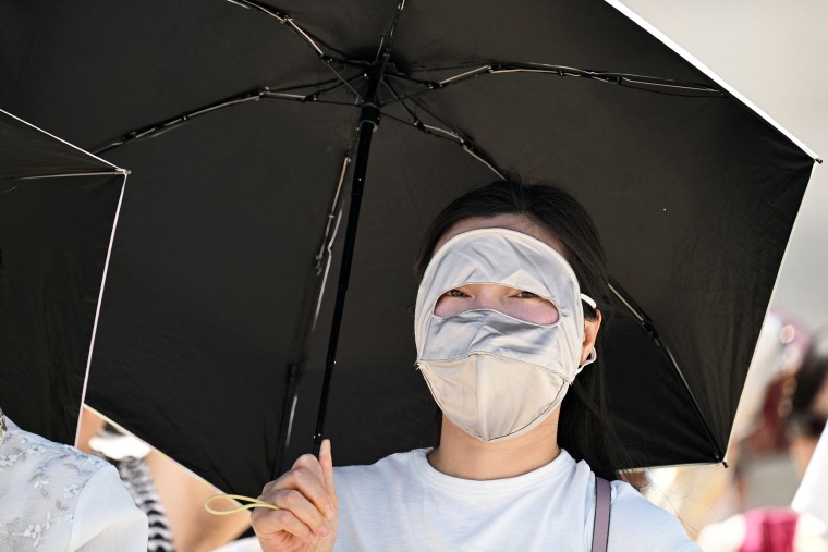 A woman wearing a full-face mask uses a parasol to shield herself from the sun at the Gyeongbokgung Palace in Seoul, South Korea, on Monday.Jung Yeon-Je / AFP via Getty Images
