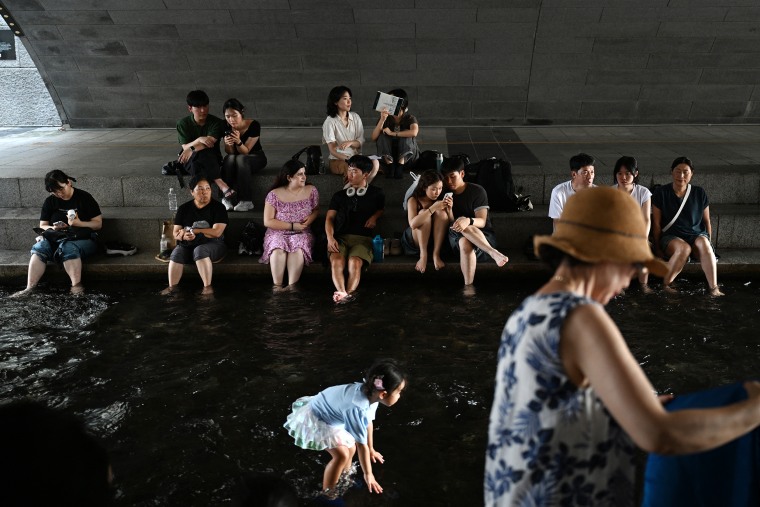 People cooling off under a bridge over the Cheonggyecheon Stream in Seoul on Monday.Greg Baker / AFP via Getty Images