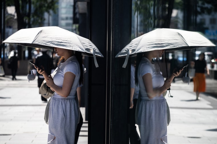 A woman uses an umbrella to take shelter from the sun on a hot morning in Tokyo last month.Andrew Caballero-Reynolds / AFP via Getty Images