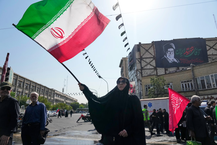 A woman waves an Iranian flag as a banner with a portrait of the late Supreme Leader Ayatollah Ali Khamenei hangs behind her in Tehran on Tuesday.Vahid Salemi / AP