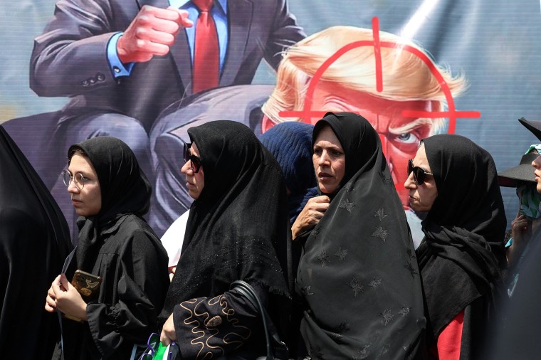 Women walk past an anti-U.S.-Israel banner during a mourning procession in Tehran on Tuesday.AFP via Getty Images