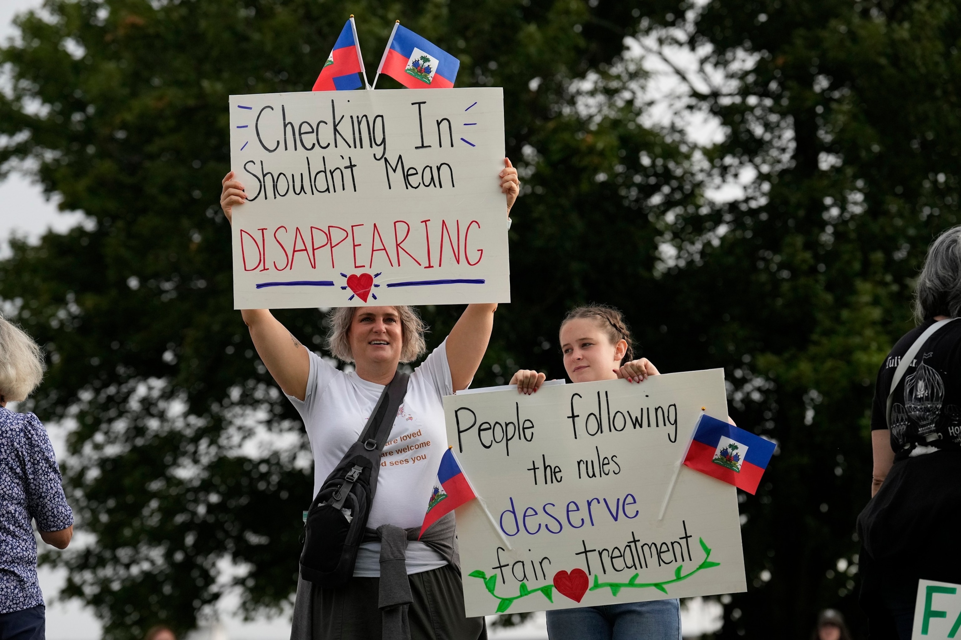 Protesters hold a signs with Haitian flags during an "ICE out of Cincinnati" protest across the street from the ICE Enforcement and Removal Operations field office as Haitians who reside in Ohio arrive for appointments in Cincinnati, Aug. 2, 2026.Carolyn Kaster/AP Photo