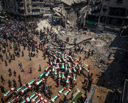 Palestinians carry the bodies through the rubble-lined streets of Deir al-Balah for burial in a nearby cemetery.Photograph: Mohammed Saber/EPA