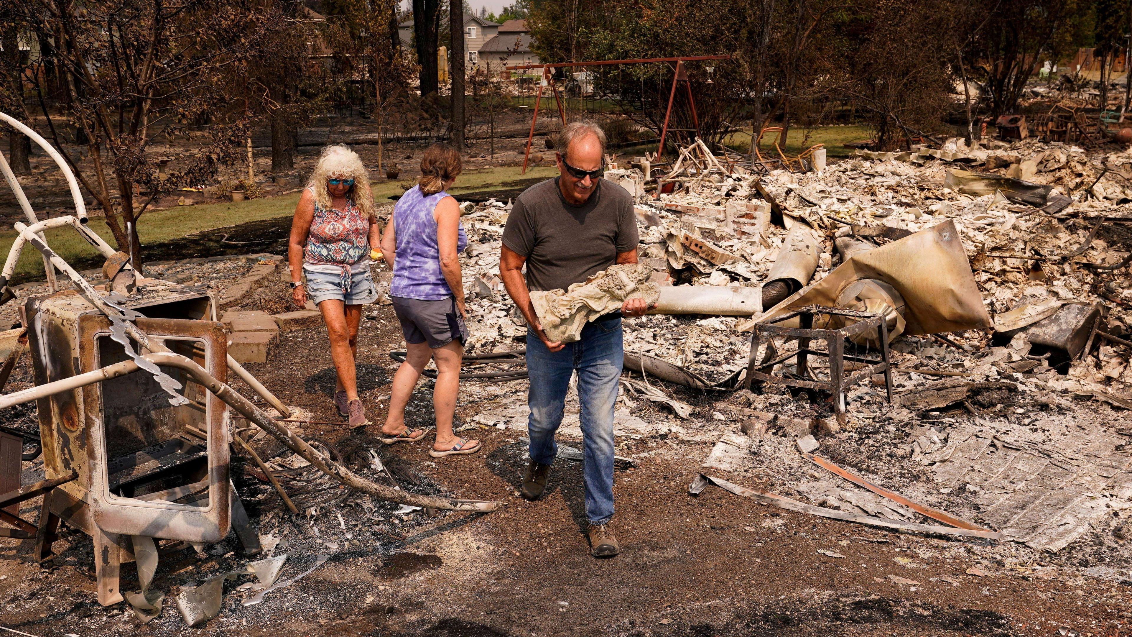 Image caption,Tim Hansen, a Spokane resident, carrying a stone angel from the ruins of a burned-out home