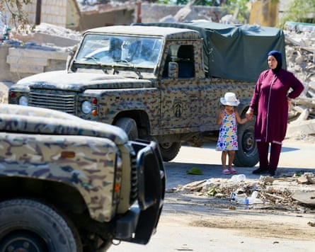 A woman and child stand next to Lebanese military vehicles in Zawtar al Gharbiya, southern Lebanon, one of the pilot zones.Photograph: EPA