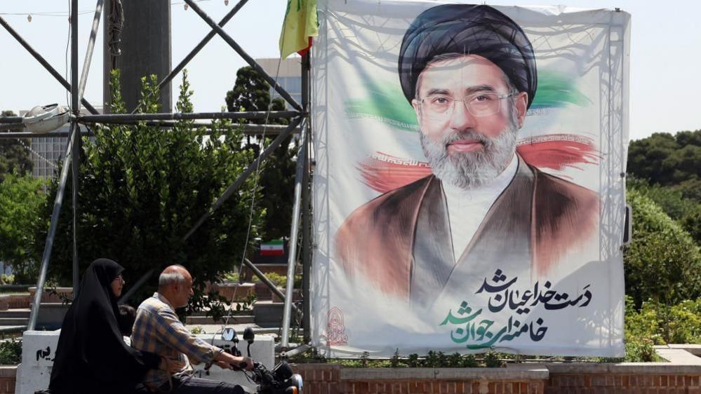 Image caption,Iranian supreme leader Ayatollah Mojtaba Khamenei, depicted in a billboard, has not appeared in public since the strike that killed his father