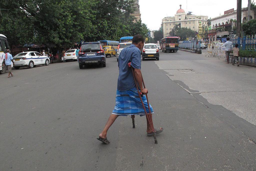 Image caption,A man with a physical disability navigates a busy road in Kolkata