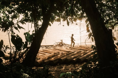 A member of the ELN’s Western War Front walks across a wooden raft on the San Juan River in southern Chocó.Photograph: Santiago Mesa/The Guardian