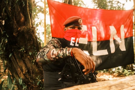 Commander Yerson stands in front of an ELN flag at a camp in southern Chocó.Photograph: Santiago Mesa/The Guardian