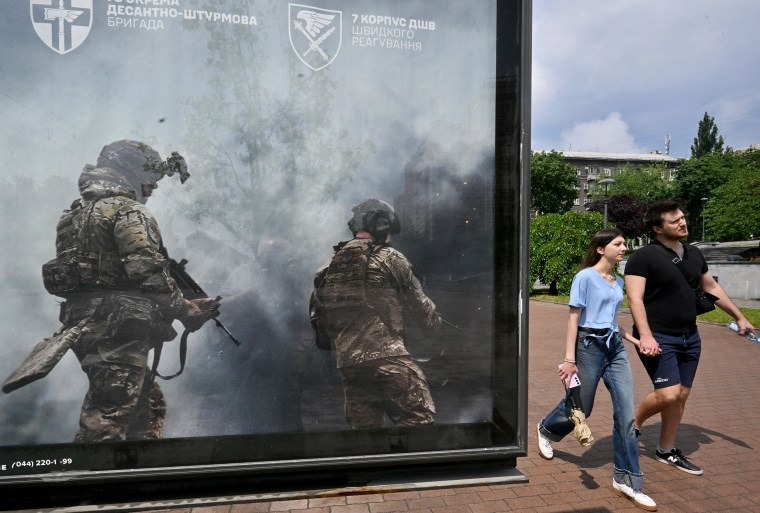 A couple walks past a recruiting placard in Kyiv in June.Sergei Supinsky / AFP via Getty Images file