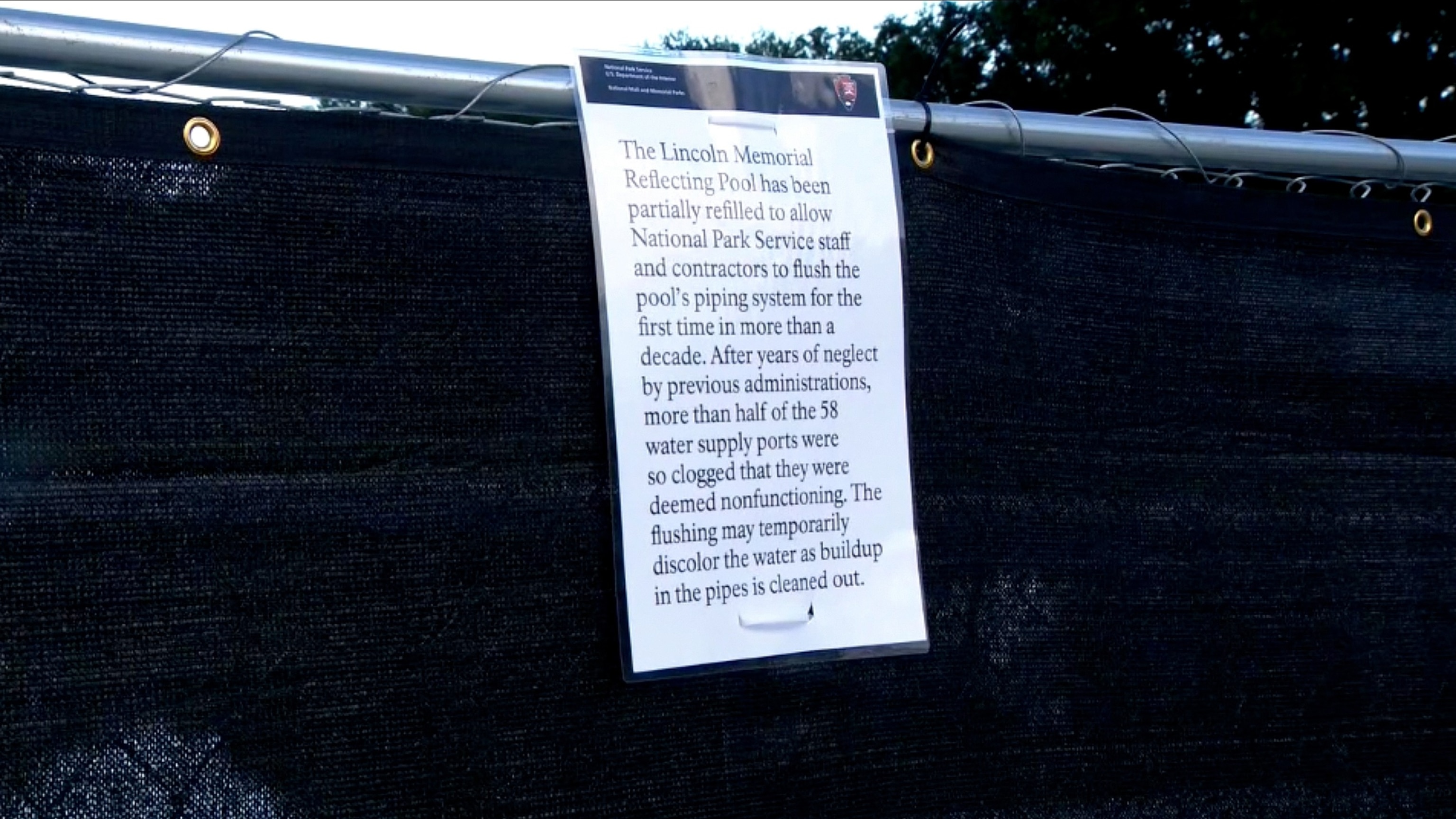 A sign placed on a fence by the National Park Service hangs next to the Lincoln Memorial Reflecting Pool, August 7, 2026 in Washington.WJLA
