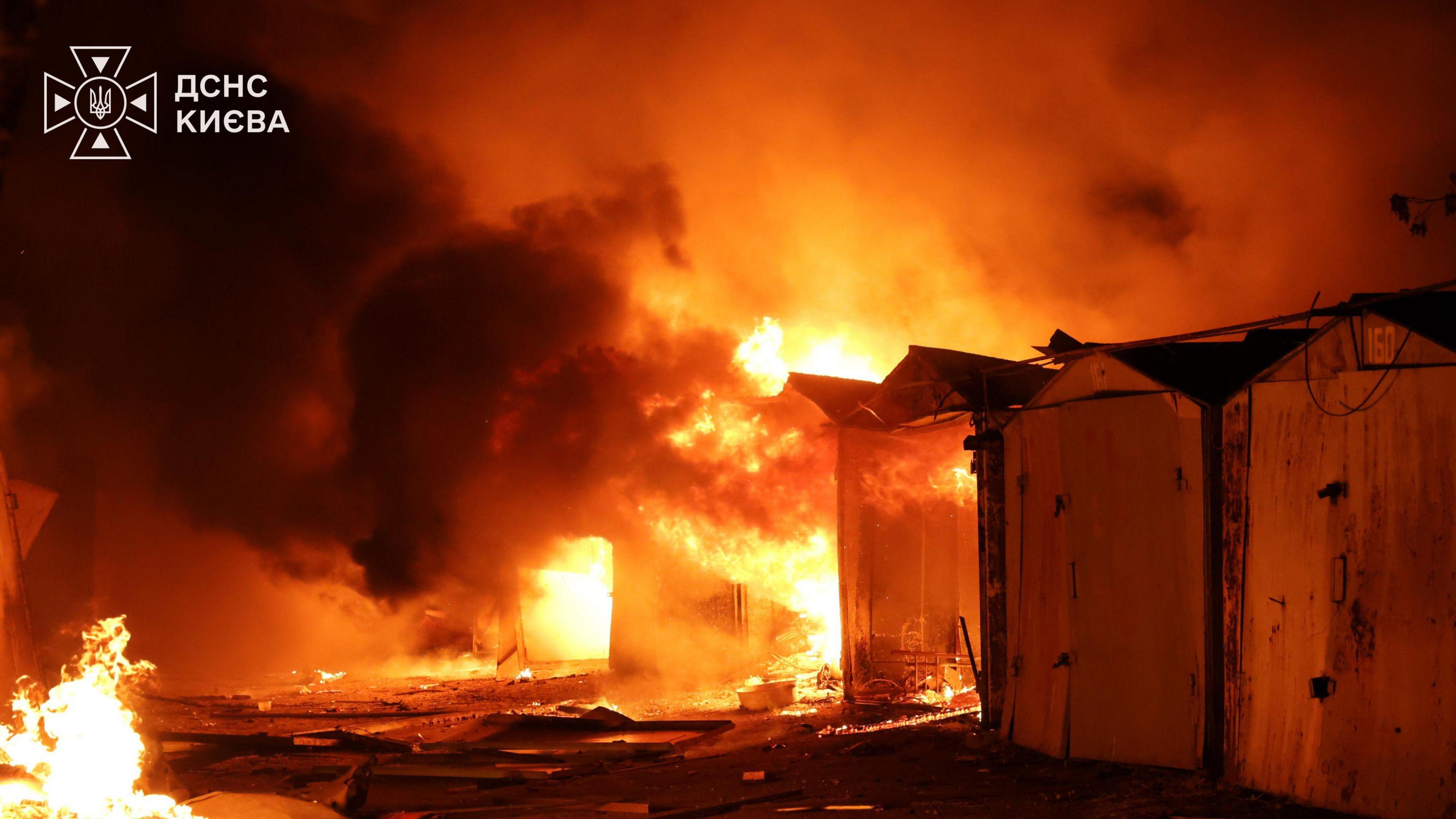 Image caption,Garages ablaze in Kyiv's Holosiivskyi district after the latest Russian strike