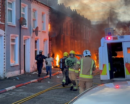 A man is escorted from his home in Belfast after rioters set fire to cars and buildings.Photograph: PA
