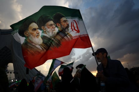 A man holds a flag with a picture of the late Ayatollah Ruhollah Khomeini, the late Ayatollah Ali Khamenei and Mojtaba Khamenei, all supreme leaders of Iran’s Islamic Republic, during a rally in Tehran on 29 April 2026.Photograph: Majid-Asgaripour/Reuters