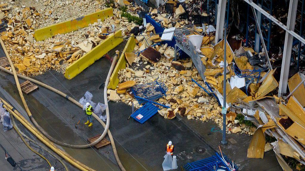 Image caption,Workers have been trying to clean up the rotting food for months