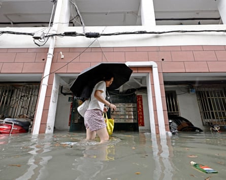 A woman wades through floodwater in Shanghai.Photograph: cnsphoto/Reuters