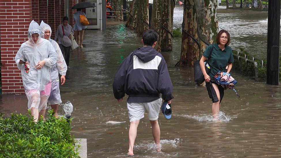 Image caption,Residents wade through flooded streets in Shanghai