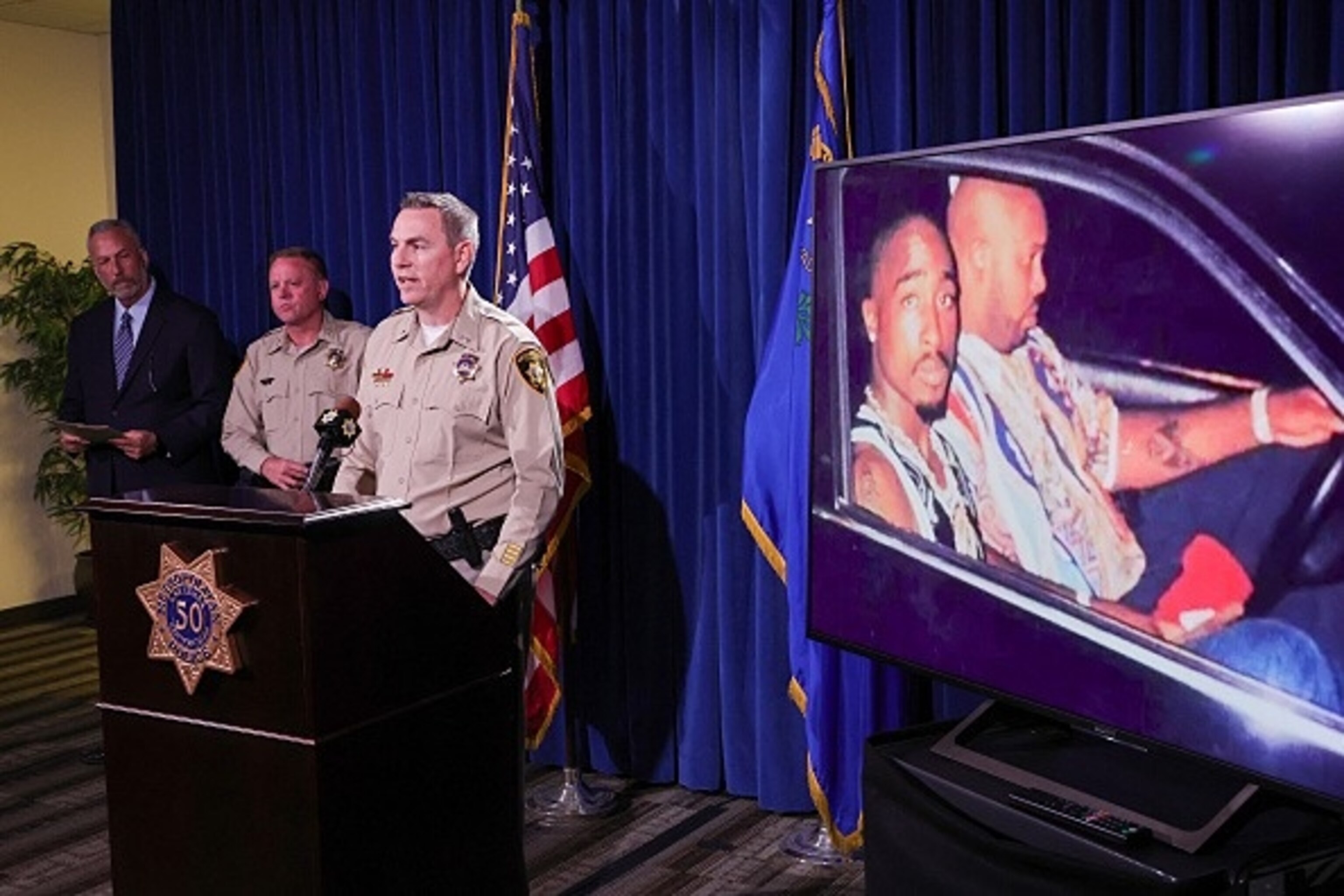 An image on a television monitor shows a photo of Tupac Shakur (L) and Marion "Suge" Knight Jr. in a car in Las Vegas the night Shakur was killed is shown at a press conference where authorities announced murder charges against Duane “Keffe D” Davis, September 29, 2023.Ethan Miller/Getty Images