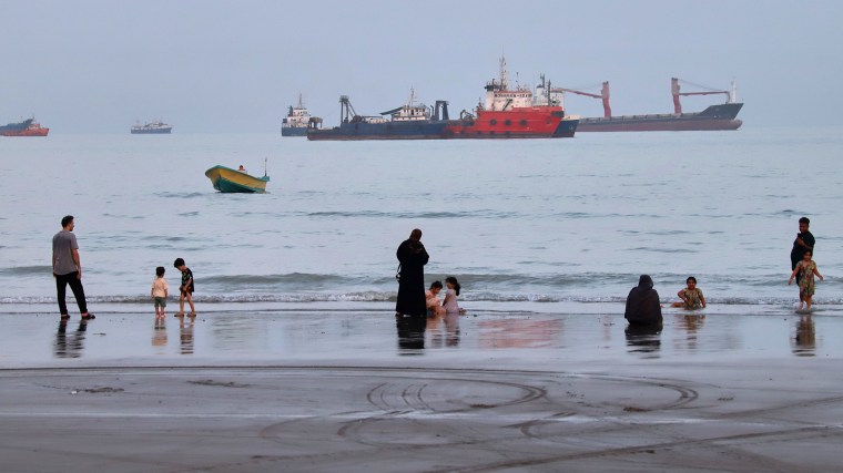 People spend time at a beach as commercial vessels are anchored in the Strait of Hormuz off Bandar Abbas, Iran on August 5.Amirhosein Khorgooi / AP