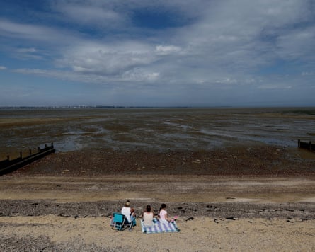 People sit on a beach at Allhallows on the Thames estuary as a yellow heat-health alert remains in force.Photograph: Kevin Coombs/Reuters