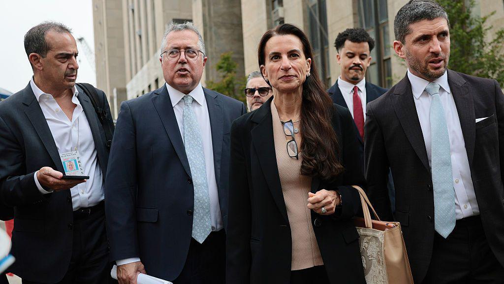 Image caption,Public spectators leave Mangione's hearing, one of them wearing a shirt that demands officials "open the courtroom".