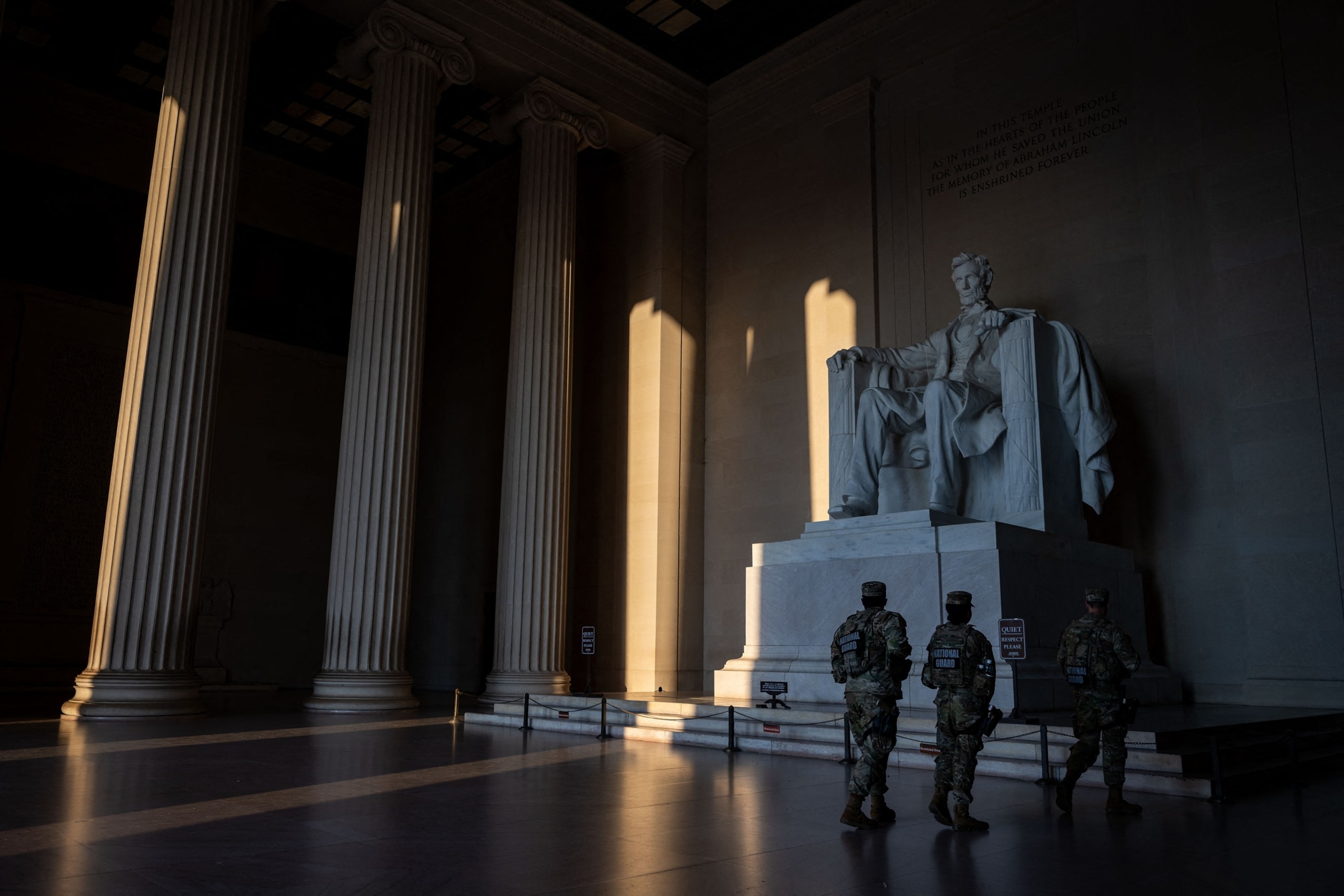 Members of the National Guard pause to look at the statue of former President Abraham Lincoln at the Lincoln Memorial at sunrise on the National Mall in Washington, D.C., July 23, 2026.Kent Nishimura/AFP via Getty Images