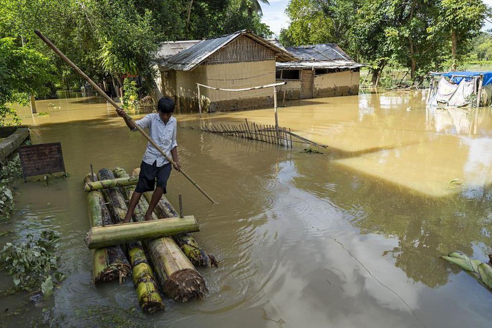 Image caption,A boy uses a makeshift banana raft to navigate floodwaters in Assam