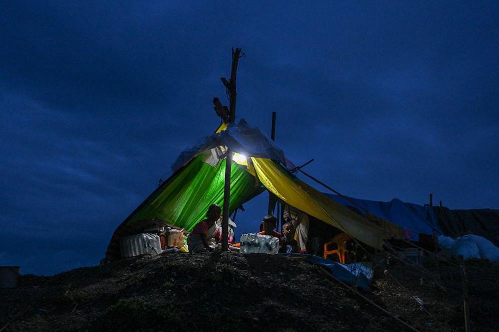 Image caption,A family shelters inside a tent in Sivasagar district, among more than 5,000 people lodged in 252 relief camps