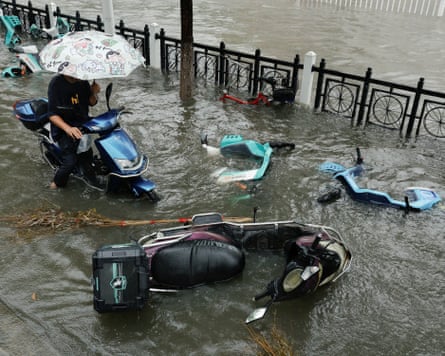 A person rides an electric scooter on a flooded street while avoiding fallen bicycles in Xiangyang, Hubei province.Photograph: Go Nakamura/Reuters