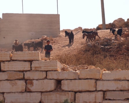 An Israeli settler tends to his animals as settlers besiege a Palestinian home.Photograph: Alaa Badarneh/EPA