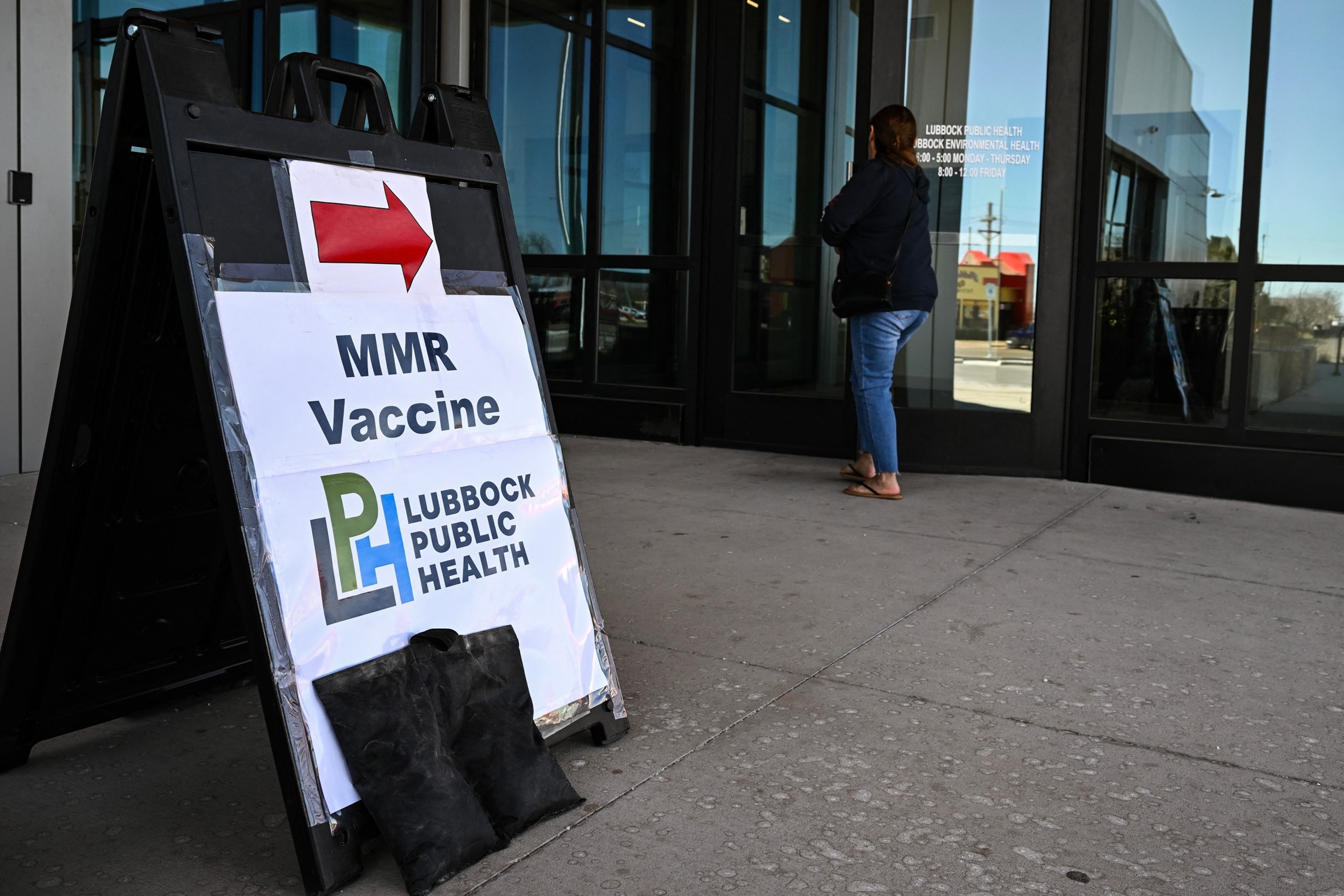 A person walks past a sign at a health center where the MMR (measles-mumps-rubella) vaccine is administered in Lubbock, Texas, Feb. 27, 2025.Ronaldo Schemidt/AFP via Getty Images
