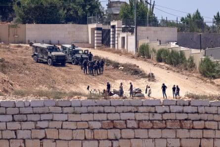Israeli soldiers stand guard next to settlers in front of Palestinian houses in the village of Qusra in the occupied West Bank on Wednesday.Photograph: Zain Jaafar/AFP/Getty