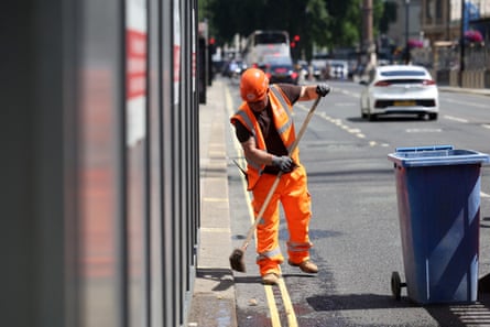 A worker sweeps the street outside a construction site during a heatwave in June.Photograph: Toby Shepheard/AFP/Getty Images