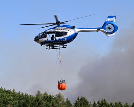 A police helicopter carries water to be dumped on wildfire in the Hürtgen forest in western Germany.Photograph: Roberto Pfeil/afp/AFP/Getty Images
