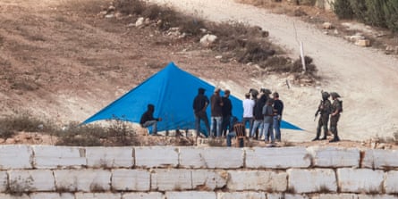 Israeli soldiers watch Israeli settlers setting up a tent just outside the entrance of a besieged Palestinian family home in the village of Qusra, in the Israeli-occupied West Bank, on 14 August 2026.Photograph: Jaafar Ashtiyeh/AFP/Getty Images