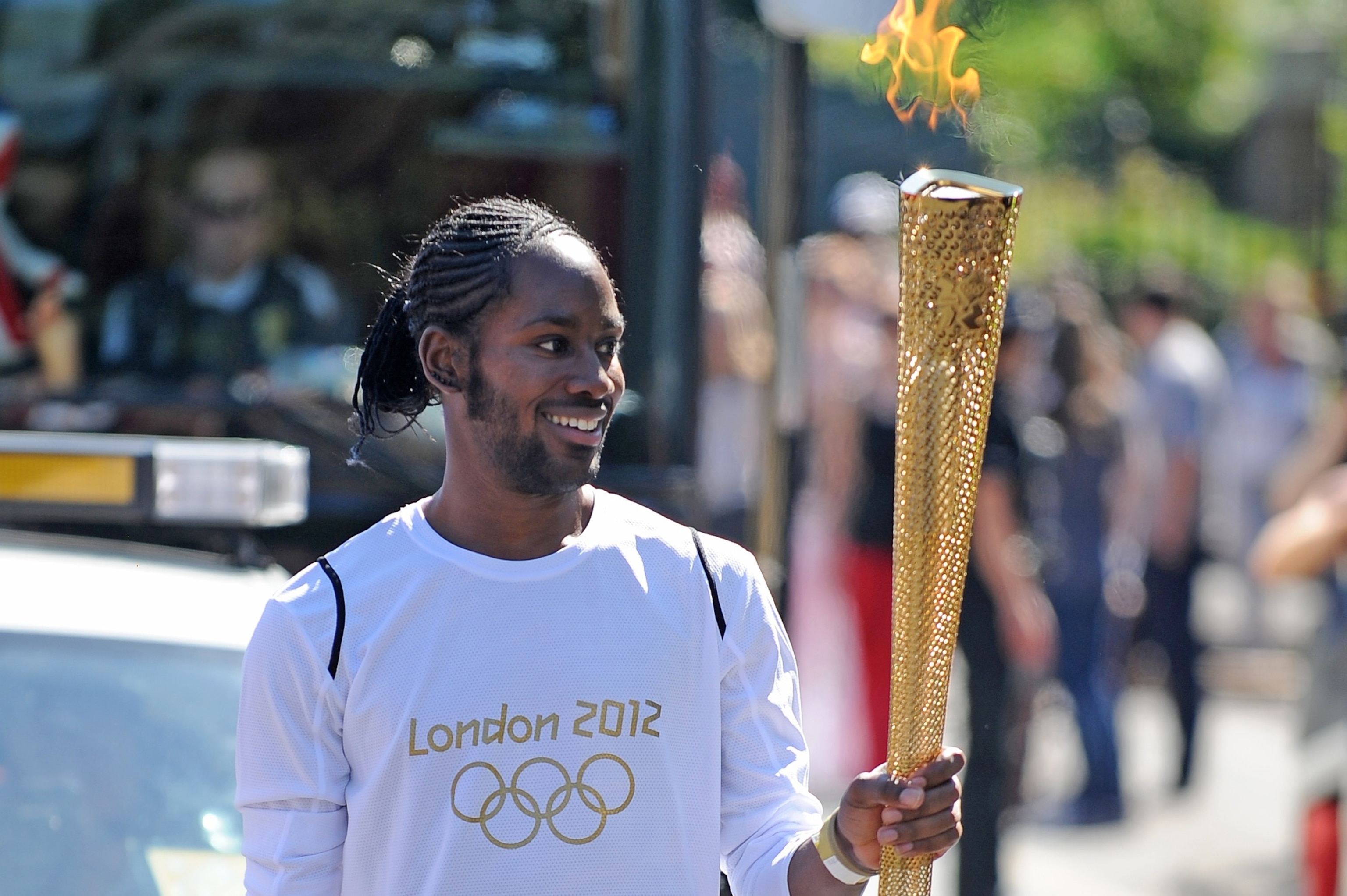 Torchbearer Jason Arday carries the Olympic Flame on the Torch Relay leg between Sutton and Merton, in London, July 23, 2012.Joe Giddens/PA via AP