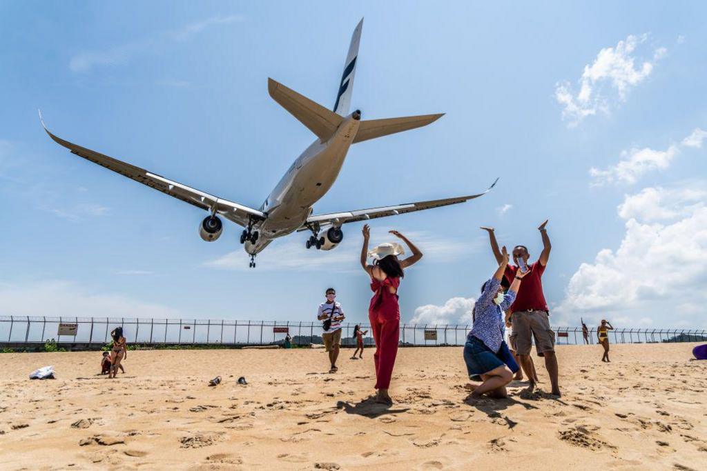 Image caption,Tourists celebrate as a plane lands at Phuket airport. The Air India plane was on a flight from Phuket to Delhi