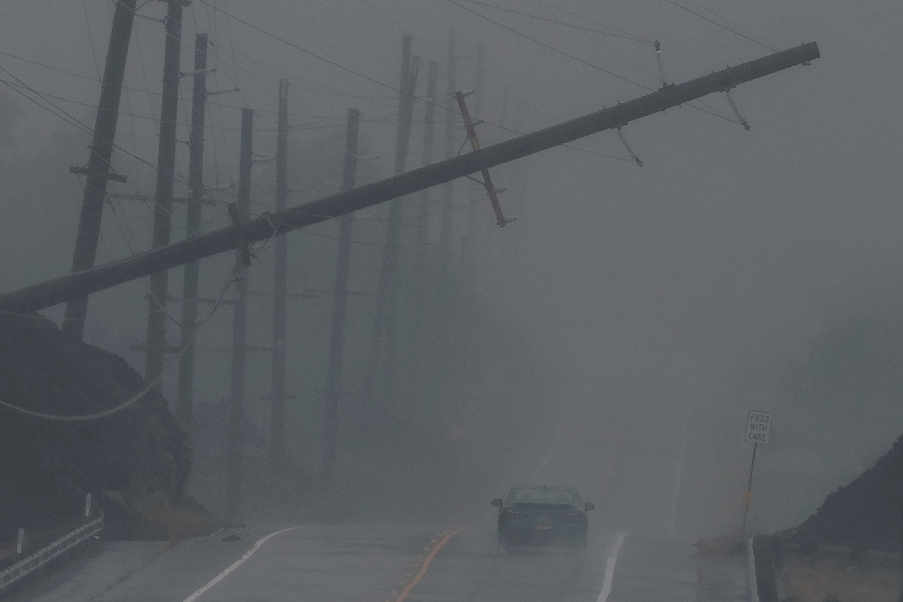 A vehicle approaches a downed utility pole dangling above Mamalahoa Highway during Hurricane Lala near Ocean View, Hawaii, Saturday, Aug. 15, 2026. The tropical storm has strengthened into a hurricane as it approaches Hawaii, with up to 25 inches of rain possible on the island of Hawaii, commonly known as the Big Island. (Photo by )San Francisco Chronicle/Hearst Newspapers/San Francisco Chronicle via Getty