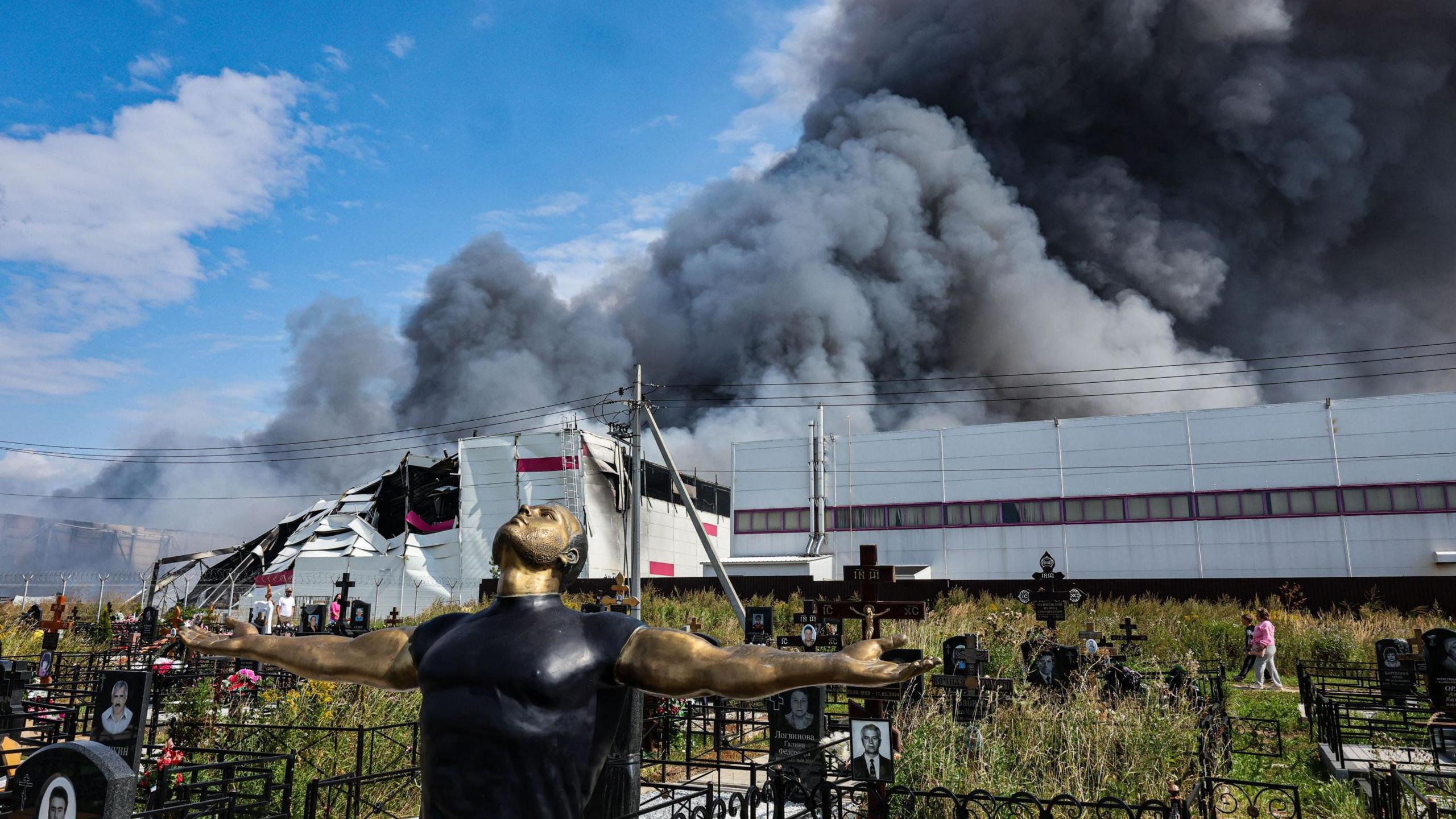 Image caption,People walking in a graveyard by a Wildberries facility near Podolsk in the Moscow region on 16 August