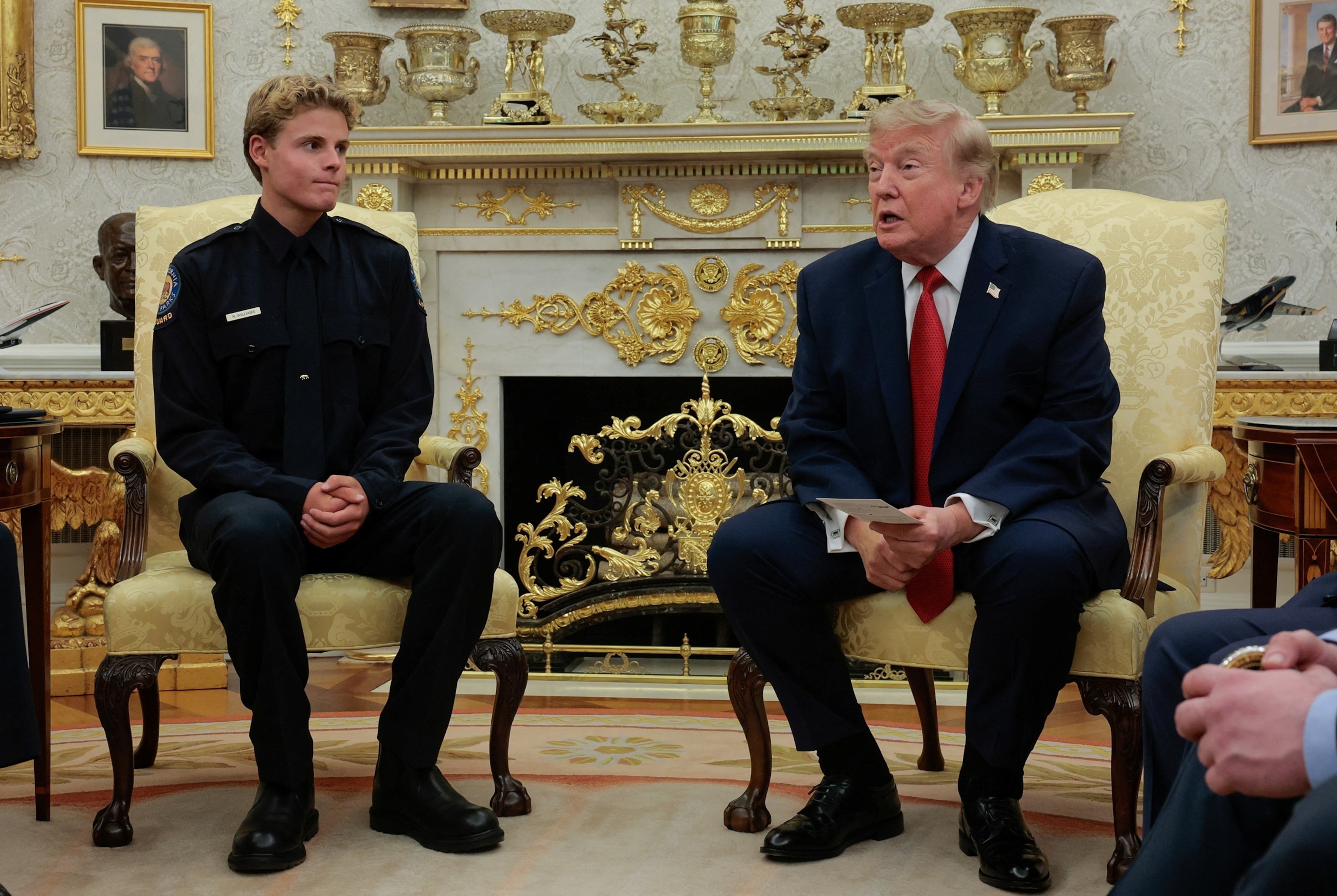 President Donald Trump sits next to 16-year-old lifeguard Ryder Williams, who saved a child off the coast of Santa Cruz, California, last month, in the Oval Office at the White House in Washington, August 17, 2026.Kylie Cooper/Reuters
