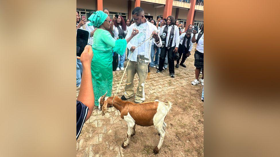 Image caption,Promise's classmates celebrated as his mother handed over the gift