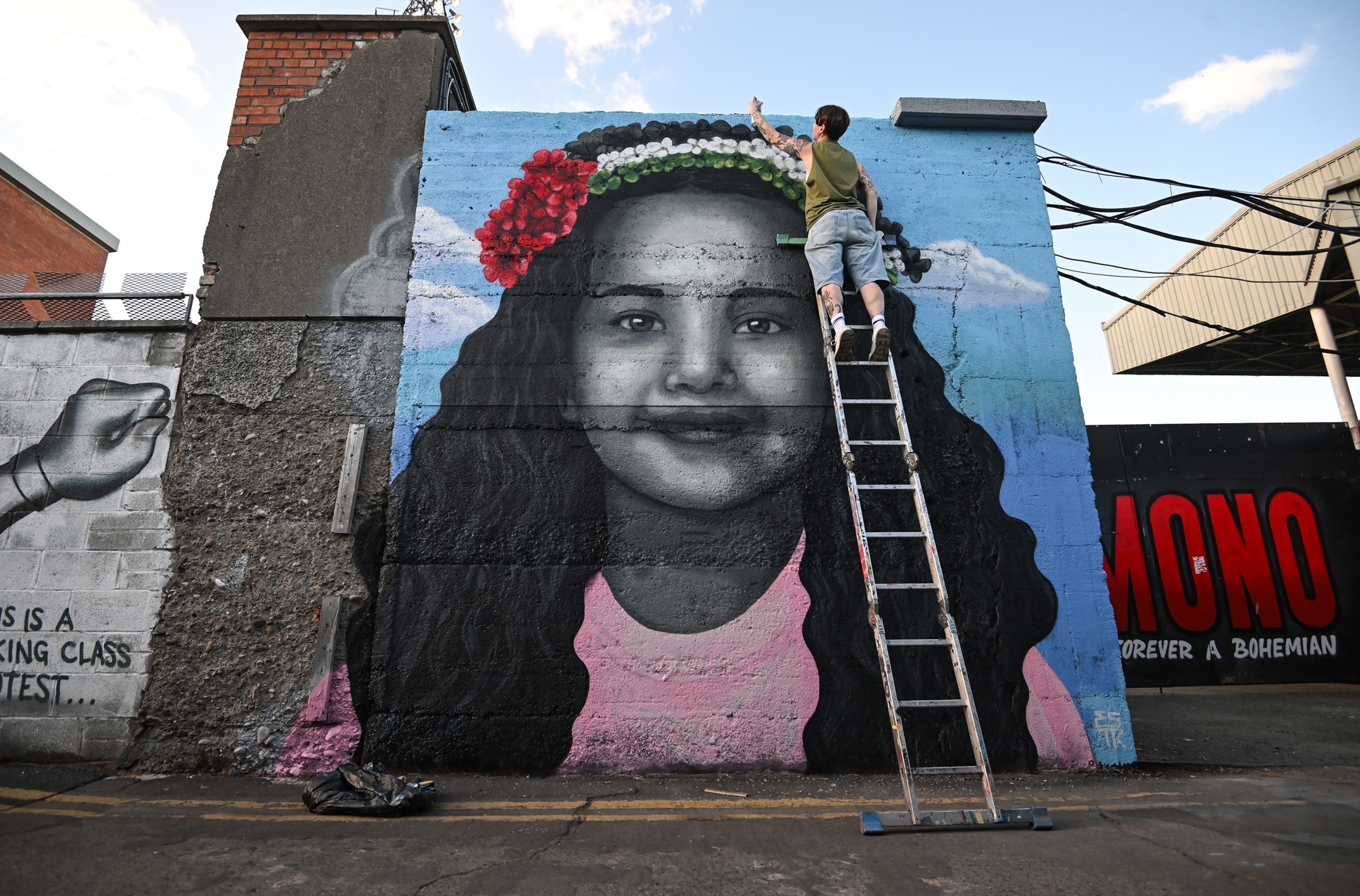 Artist Emmalene Blake puts the final touches to a mural of Hind Rajab, the 5-year-old Palestinian girl who was killed in Gaza, before the international solidarity soccer match between Bohemians and Palestine at Dalymount Park in Dublin, May 15, 2024..Stephen Mccarthy/Sportsfile via Getty Images