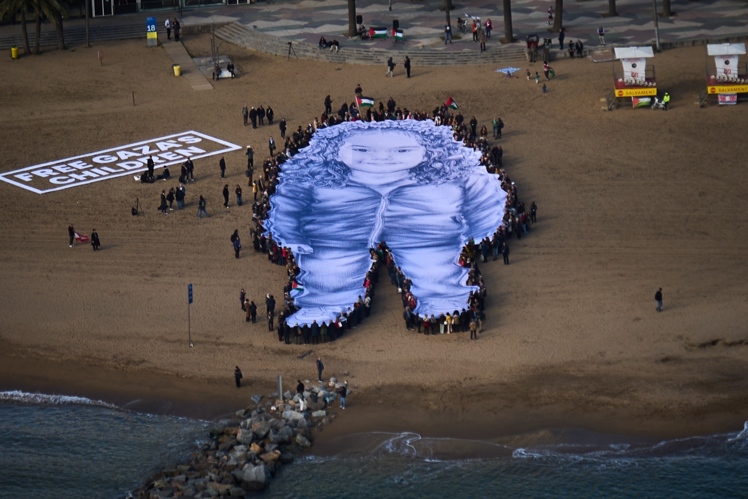 People hold a giant portrait of Hind Rajab, a five-year-old Palestinian girl who was killed during the war in Gaza, on a beach in Barcelona, Spain, Jan. 29, 2026.Emilio Morenatti/AP