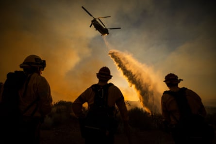 A helicopter drops water on the Summit fire in Llano, California, last month.Photograph: Ethan Swope/AP