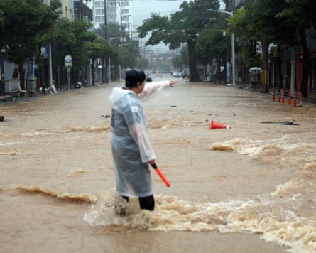 A police officer standing in a flooded road in Geoje, South Korea.Photograph: Yonhap News Agency/Reuters