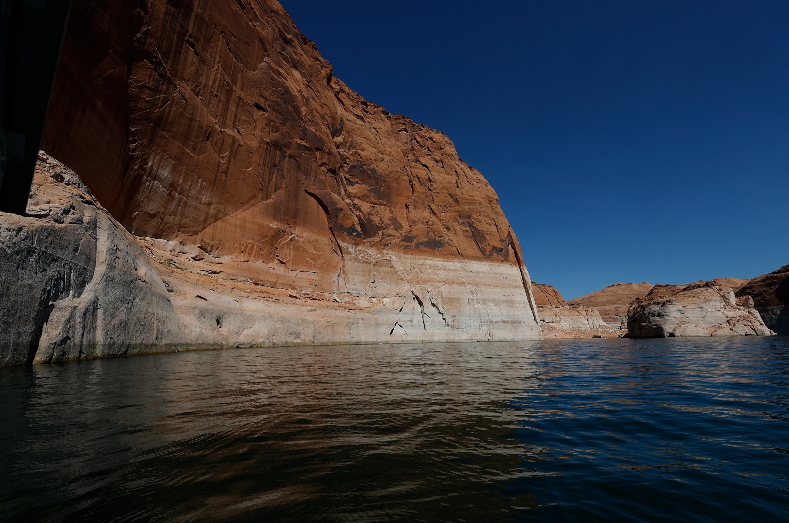 PAGE, ARIZONA - AUGUST 01: The tall bleached ''bathtub ring'' is visible on the rocky banks of Lake Powell on August 01, 2026 in Page, Arizona. In July, the combined water of Lake Mead and Lake Powell, the country's two biggest reservoirs, fell to their lowest levels since 1957. The unprecedented low in combined storage prompted the U.S. Department of the Interior to mandate twenty percent cuts in water usage for the next two years for Arizona, California and Nevada.Justin Sullivan/Getty Images