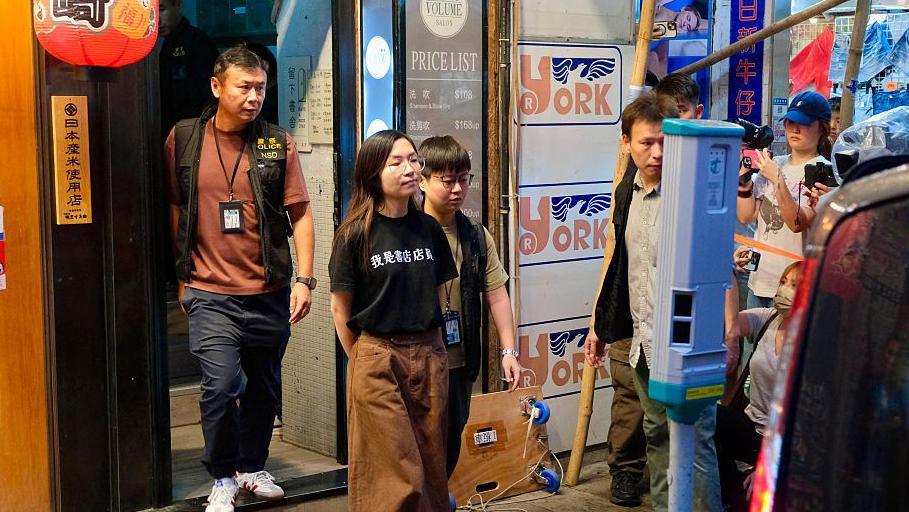 Image caption,Police escort a worker out of Have a Nice Stay bookstore, whose t-shirt reads 'I am a bookshop employee'